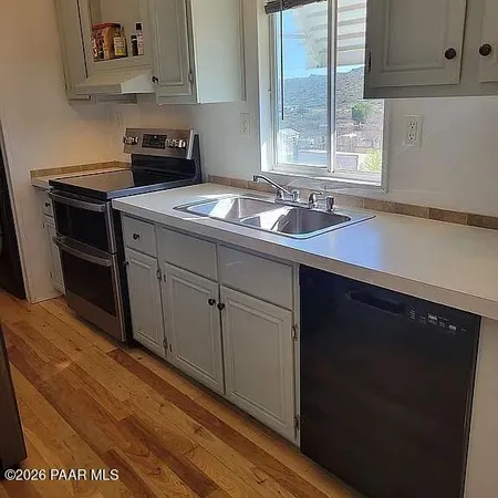 a kitchen with stainless steel appliances granite countertop a sink dishwasher a stove and a refrigerator with wooden floor