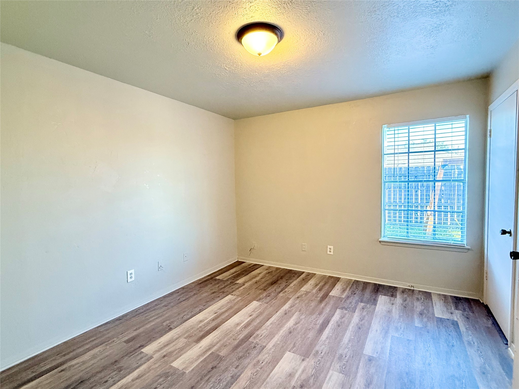 705 Ruth Court, Unit B Navasota, TX 77868 - Photo 11 of 14 an empty room with wooden floor and windows