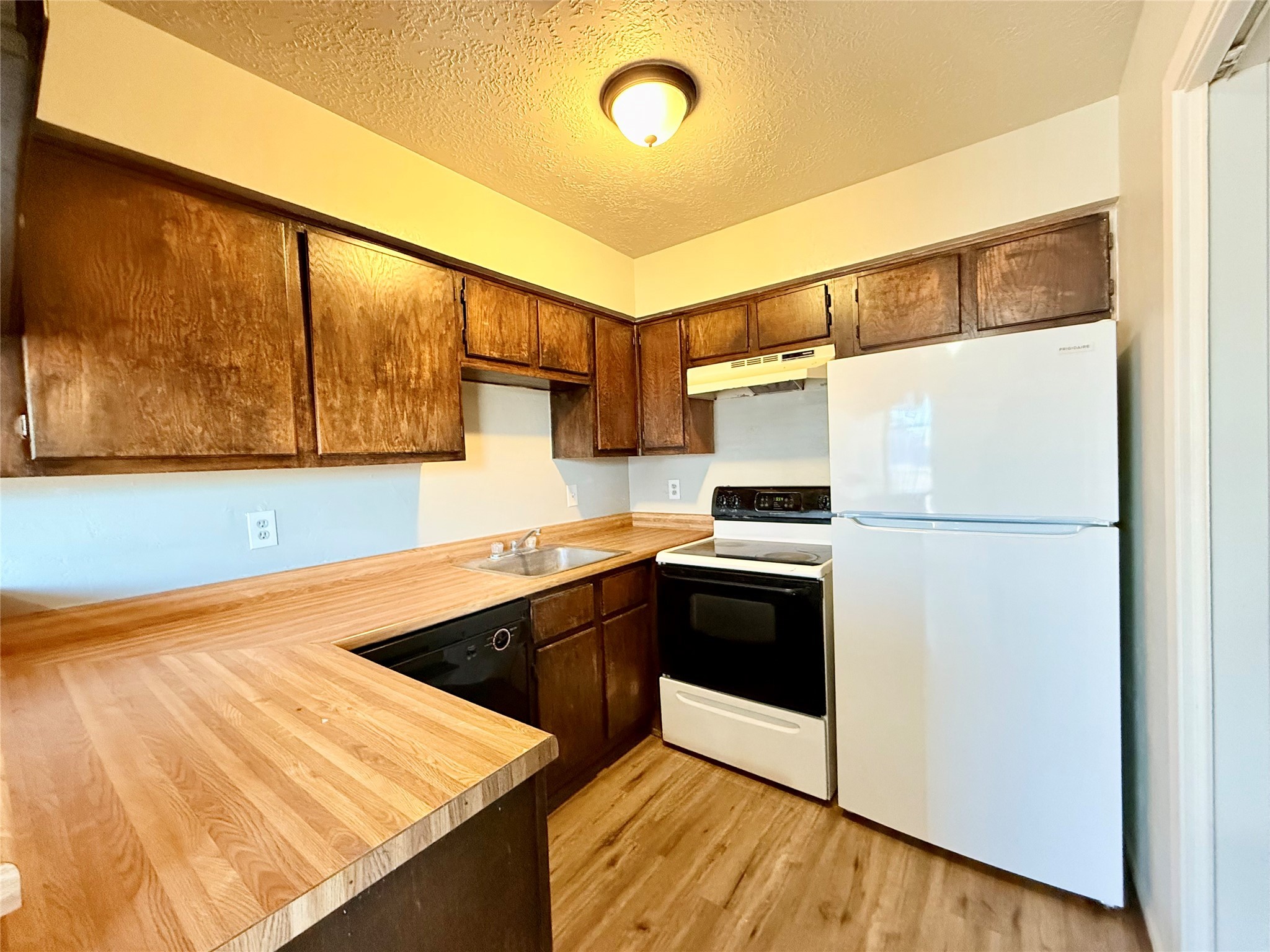 705 Ruth Court, Unit B Navasota, TX 77868 - Photo 3 of 14 a kitchen with stainless steel appliances granite countertop a refrigerator a stove and a sink with wooden floor