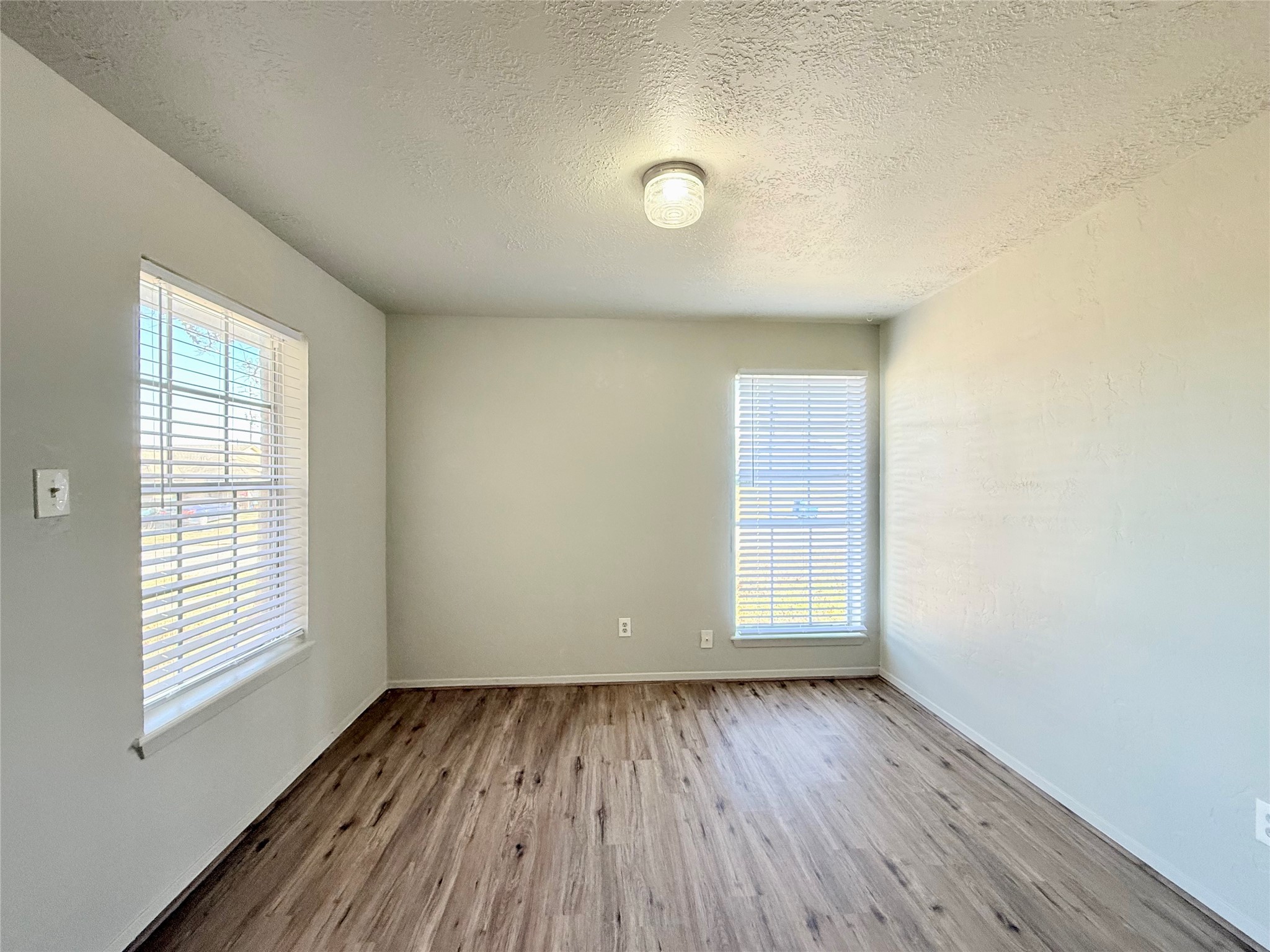 705 Ruth Court, Unit B Navasota, TX 77868 - Photo 6 of 14 an empty room with wooden floor and windows