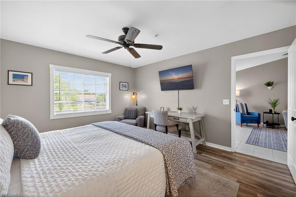9009 Michael Circle, Unit 4 Naples, FL 34113 - Photo 15 of 34 a bedroom with a bed a chandelier and a flat screen tv