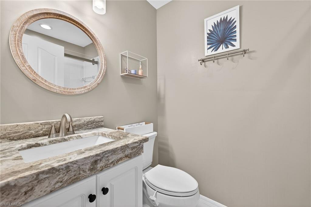 9009 Michael Circle, Unit 4 Naples, FL 34113 - Photo 22 of 34 a bathroom with a granite countertop toilet a sink and a mirror