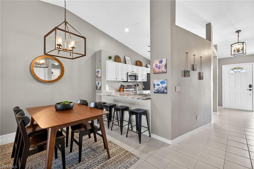 9009 Michael Circle, Unit 4 Naples, FL 34113 - Photo 7 of 34 a kitchen with a dining table and chairs