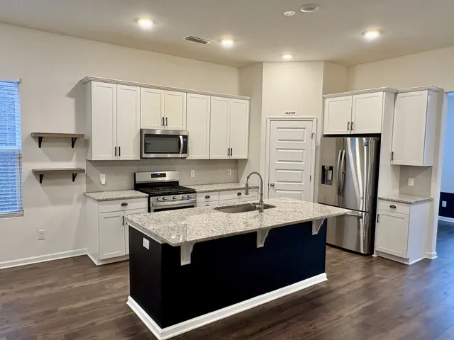 a kitchen with stainless steel appliances granite countertop a stove a refrigerator and a microwave