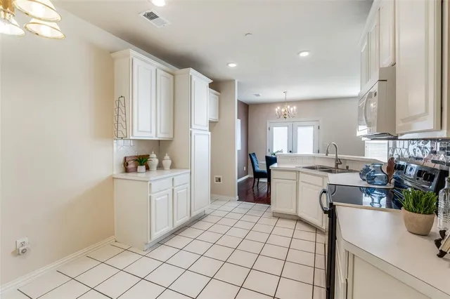 a kitchen with a sink dishwasher stove and white cabinets