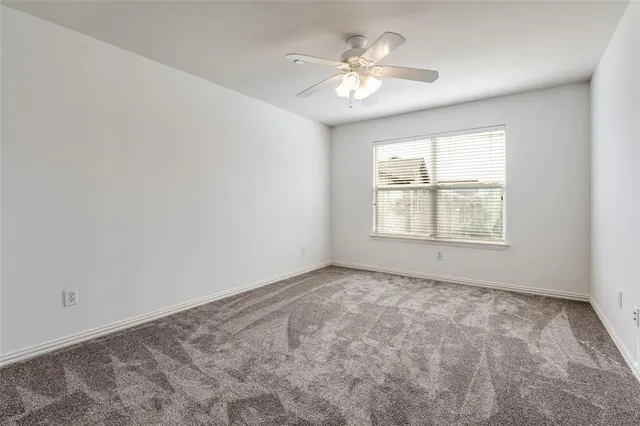an empty room with windows and chandelier fan