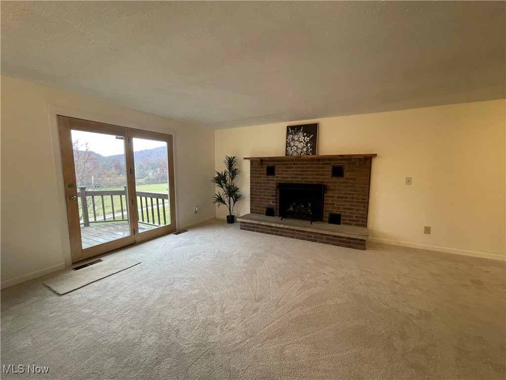 1984 Hebron Road St. Marys, WV 26170 - Photo 15 of 33 Unfurnished living room featuring carpet floors, baseboards, and a brick fireplace