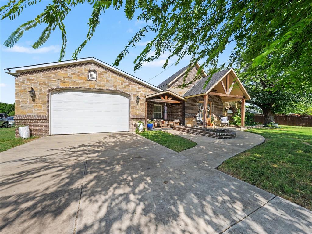 6701 Nauert Road Forest Hill, TX 76140 - Photo 2 of 40 Stone and brick exterior featuring a covered entry porch with timber accents, a second covered porch, a concrete driveway, and an attached garage with an arched opening