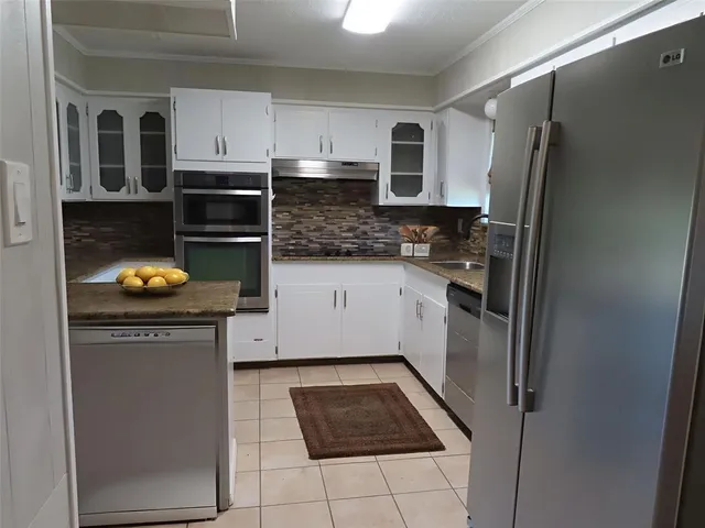 a kitchen with granite countertop a refrigerator stove and sink