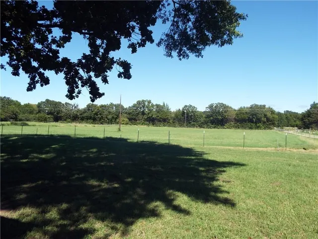 a view of a green field with wooden fence