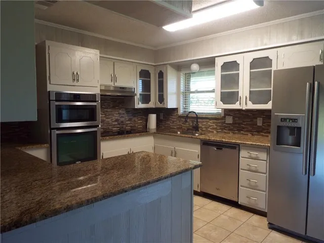 a kitchen with granite countertop a refrigerator and a stove