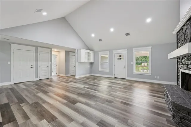 an empty room with wooden floor fireplace and windows