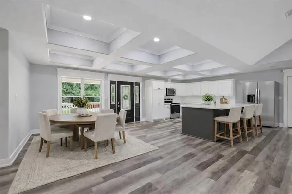 a large white kitchen with kitchen island a stove a sink a refrigerator and white cabinets with wooden floor