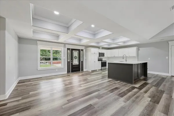 an empty room with wooden floor fireplace and windows