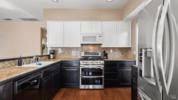 a kitchen with stainless steel appliances a stove a sink and wooden floors
