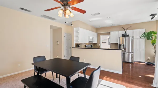 a kitchen with stainless steel appliances granite countertop a dining table chairs and a refrigerator