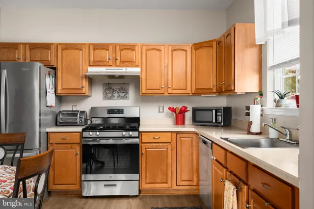 a kitchen with stainless steel appliances granite countertop a stove a sink and a refrigerator