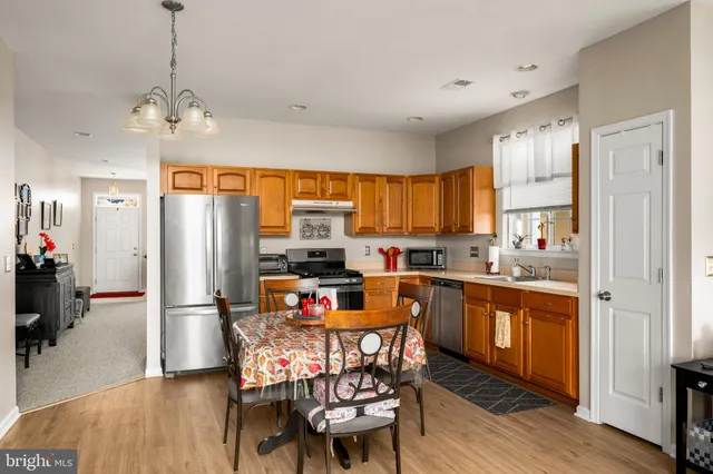 a kitchen with stainless steel appliances a dining table chairs refrigerator and sink