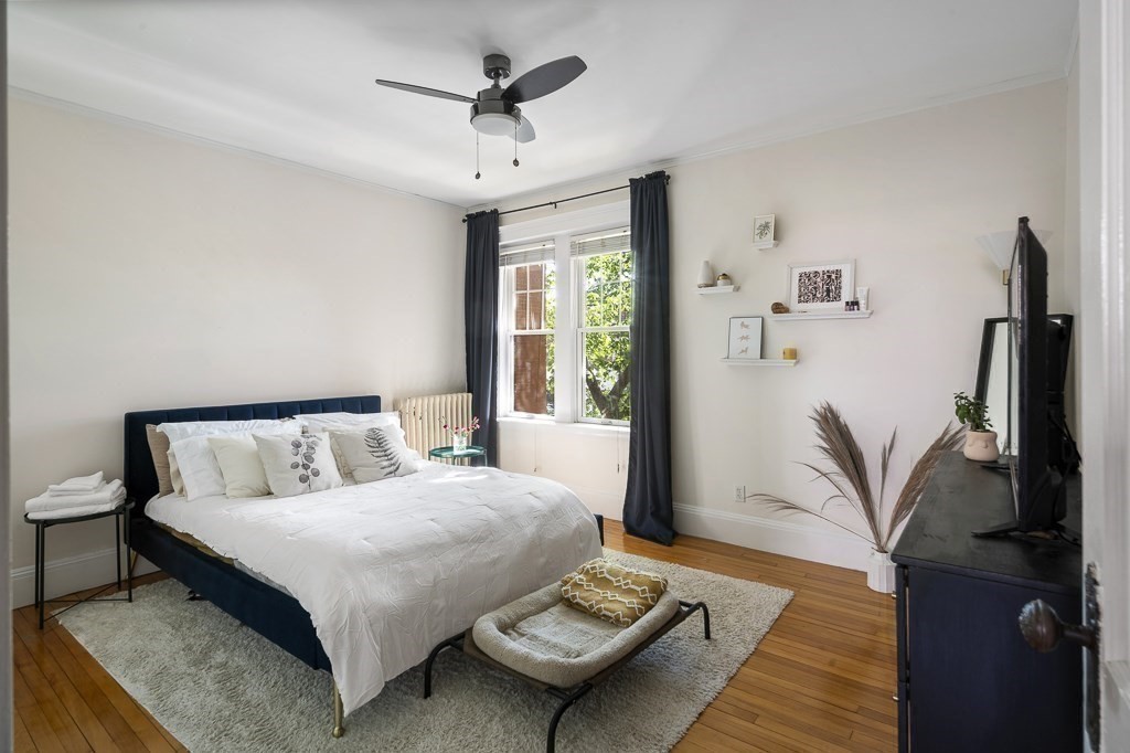 231 Rawson Road, Unit 6 Brookline, MA 02445 - Photo 8 of 11 a bedroom with a bed wooden floor and a flat screen tv