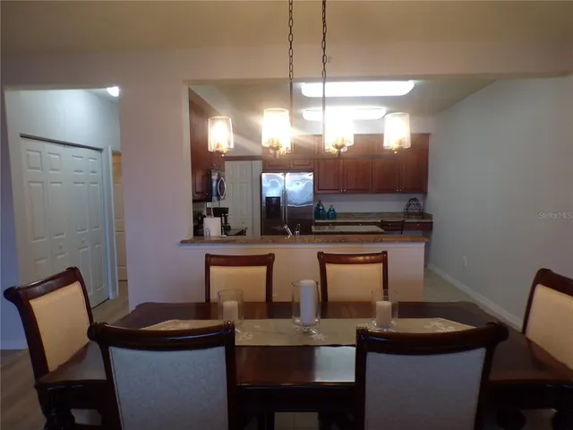 a kitchen with a dining table chairs and a refrigerator