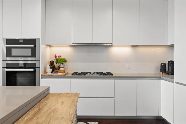 a kitchen with granite countertop white cabinets and stainless steel appliances