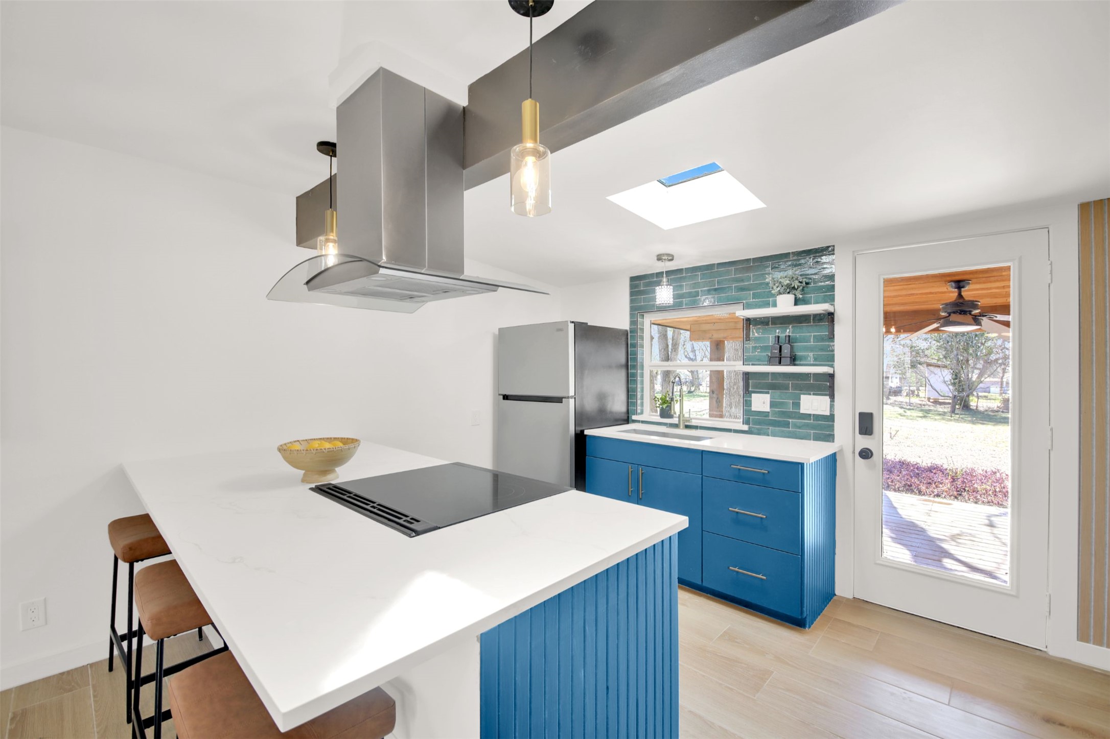 8904 Chisholm Lane Austin, TX 78748 - Photo 21 of 40 Kitchen featuring blue cabinetry, a breakfast bar, a peninsula, island range hood, and freestanding refrigerator