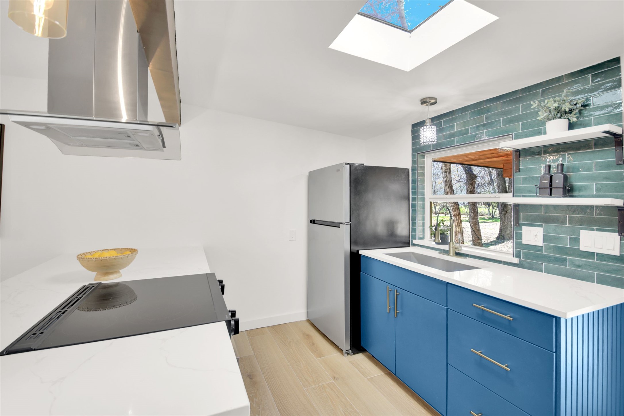 8904 Chisholm Lane Austin, TX 78748 - Photo 22 of 40 Kitchen featuring blue cabinets, island range hood, a skylight, open shelves, and freestanding refrigerator