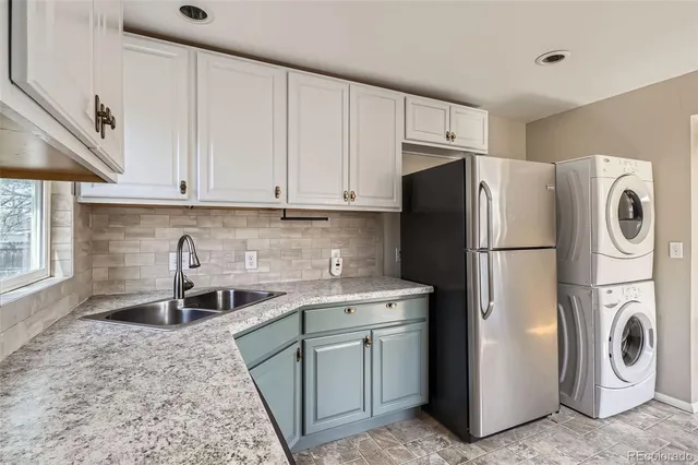 a kitchen with stainless steel appliances granite countertop a refrigerator a washer and dryer