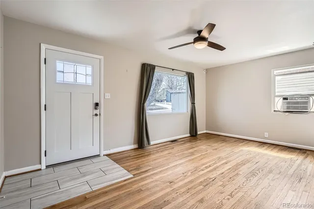 a view of an empty room with wooden floor and a window