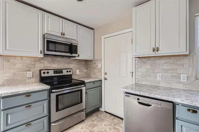 a kitchen with granite countertop white cabinets and stainless steel appliances