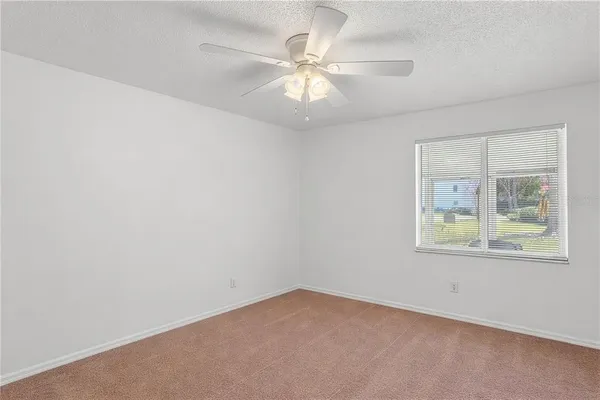 an empty room with a window and a fan