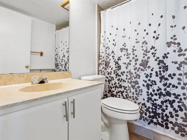 a bathroom with a granite countertop sink a toilet and a mirror