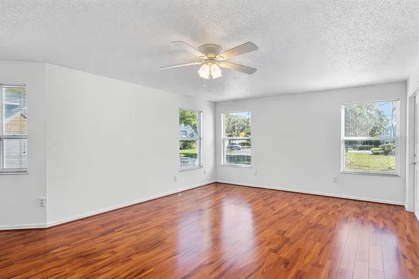 a view of an empty room with wooden floor and a window