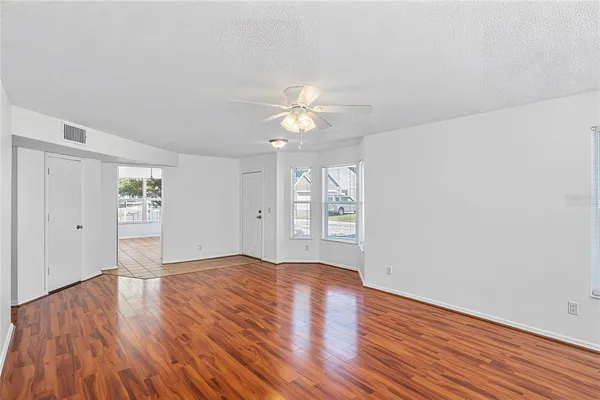 a view of an empty room with window and wooden floor