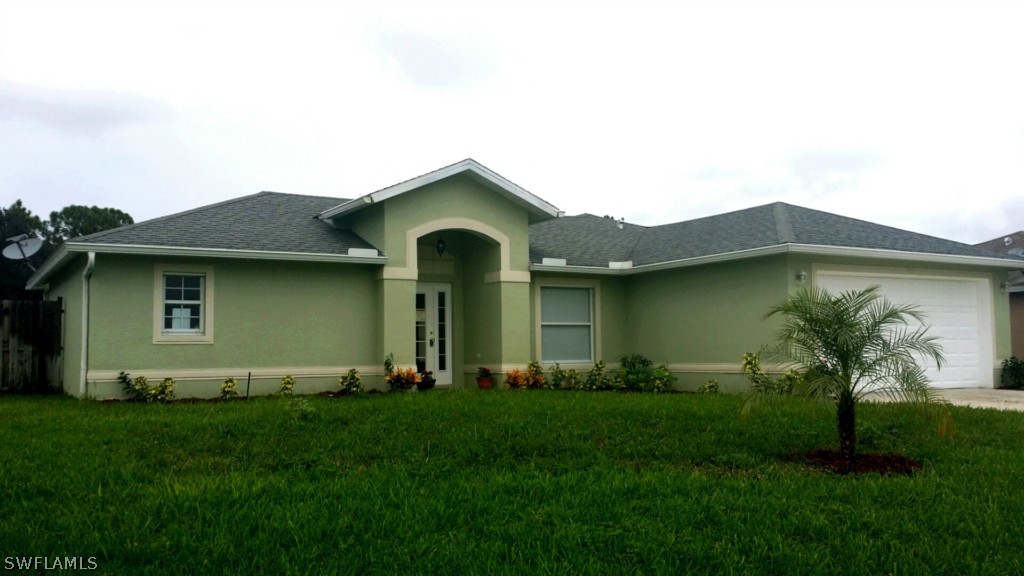 134 Ridgemont Drive Lehigh Acres, FL 33972 - Photo 1 of 14 a front view of a house with a garden and plants