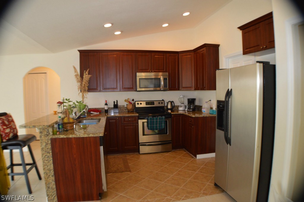 134 Ridgemont Drive Lehigh Acres, FL 33972 - Photo 5 of 14 a kitchen with stainless steel appliances granite countertop a refrigerator and a stove top oven
