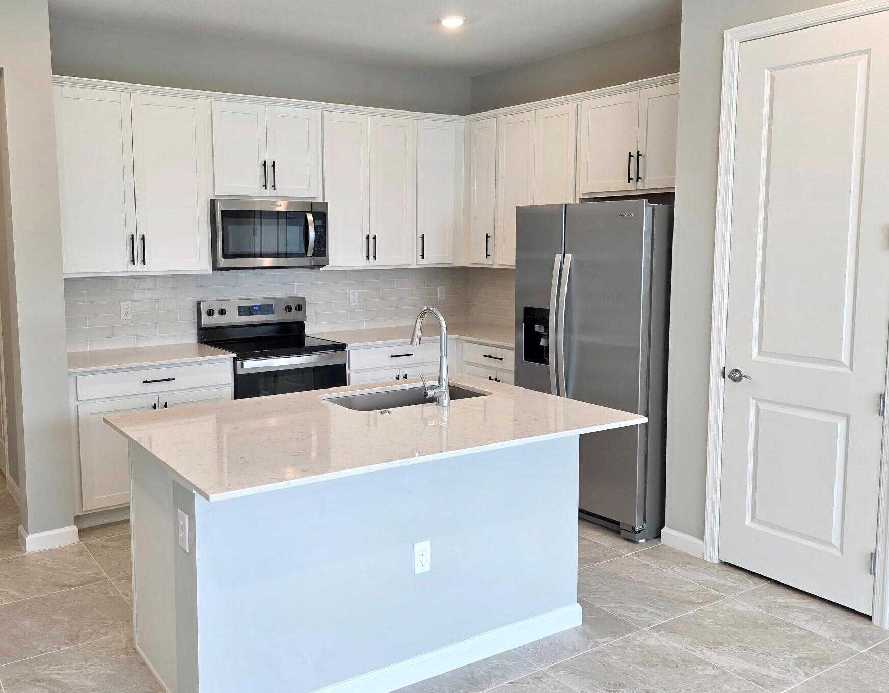 288 Southwest Sally Way, Unit LATITUDE 6112 Stuart, FL 34997 - Photo 8 of 22 a kitchen with stainless steel appliances a refrigerator stove microwave and sink