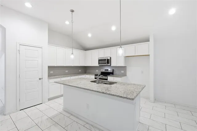 a kitchen with kitchen island granite countertop a sink a counter top space and appliances