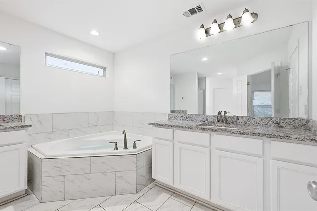 a bathroom with a granite countertop bathtub sink and mirror