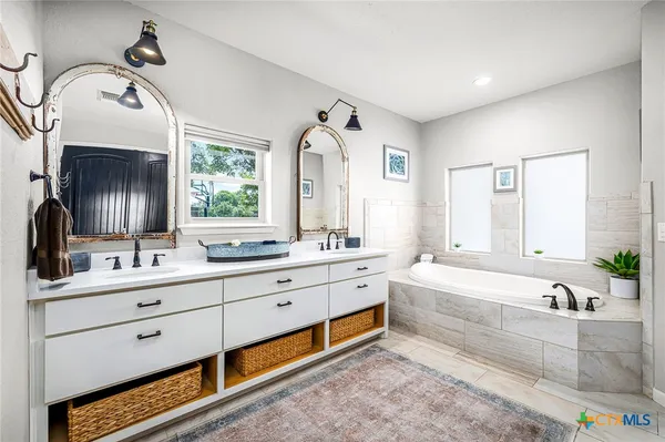 a spacious bathroom with a double vanity sink mirror and bathtub