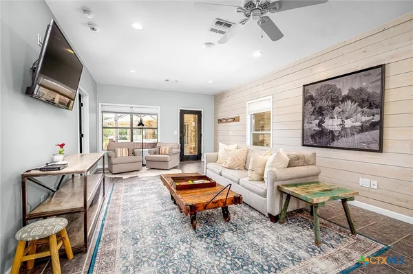 a living room with furniture a flat screen tv and a window