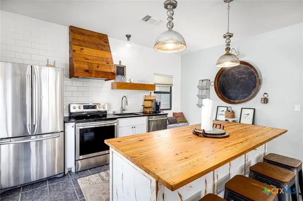 a kitchen with stainless steel appliances granite countertop a sink a stove and refrigerator