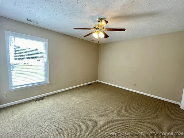 a view of an empty room and chandelier fan