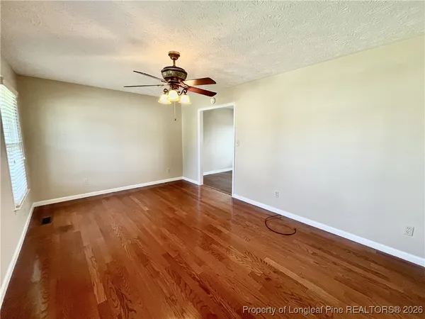 a view of a room with wooden floor and a ceiling fan