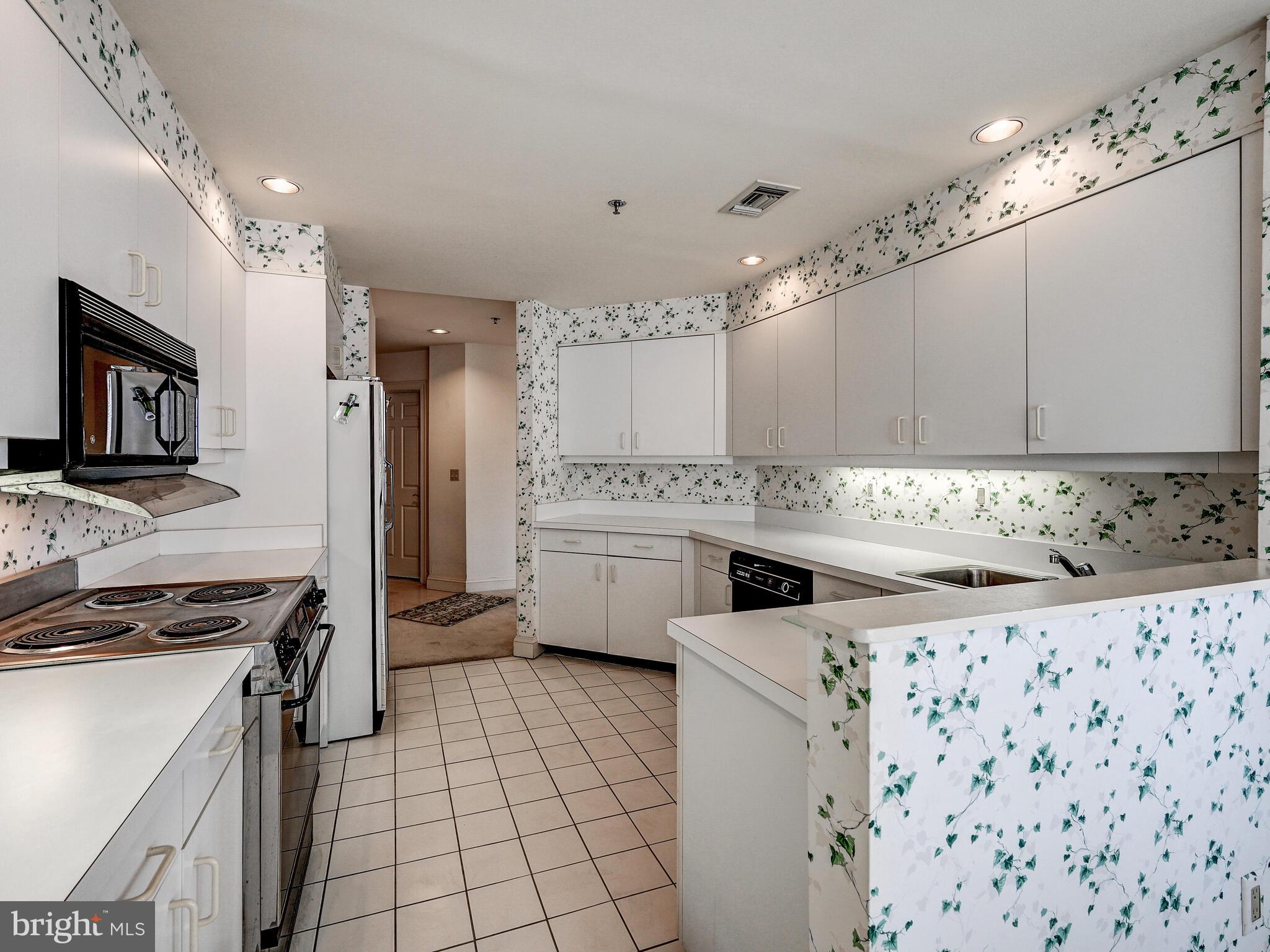 3704 North Charles Street, Unit 505 Baltimore, MD 21218 - Photo 13 of 34 a kitchen with white cabinets a sink stove and refrigerator