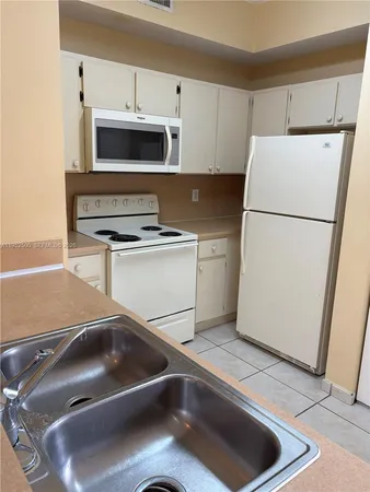 a kitchen with a refrigerator sink and white cabinets