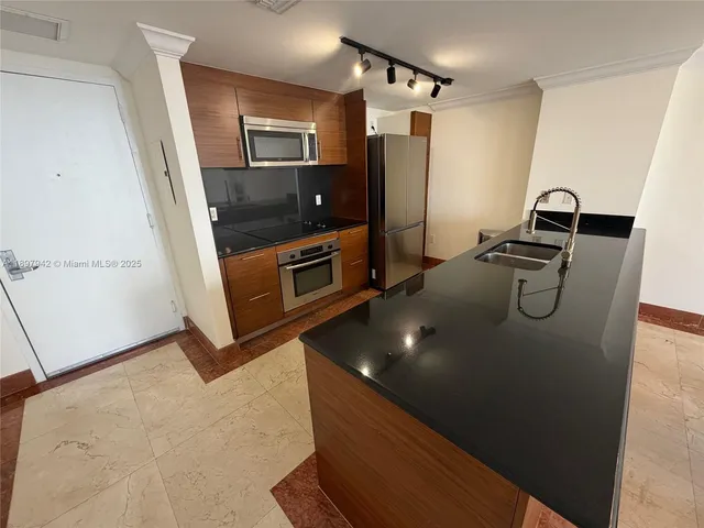 a kitchen with granite countertop a refrigerator and a sink