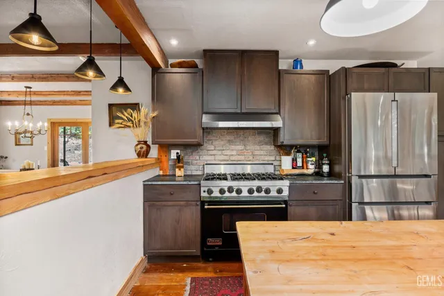 a kitchen with stainless steel appliances granite countertop a refrigerator a stove and a sink