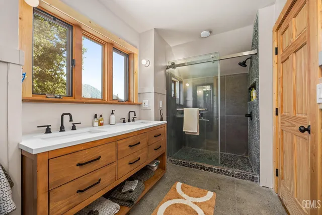 a bathroom with a granite countertop sink a mirror a glass door and shower