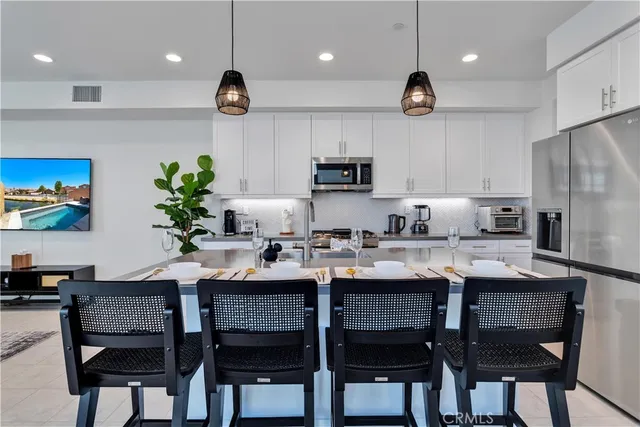 a kitchen with stainless steel appliances granite countertop a stove a refrigerator a sink a dining table and chairs with wooden floor